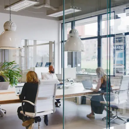 Office space rental at Torenallee 20, Eindhoven Strijp-S, featuring a modern interior with glass walls and people engaged in business activities at desks.