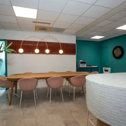 Furnished office at Boddenkampsingel 95 in Enschede with a long wooden table, pink chairs, and a dartboard, available for office space rental.