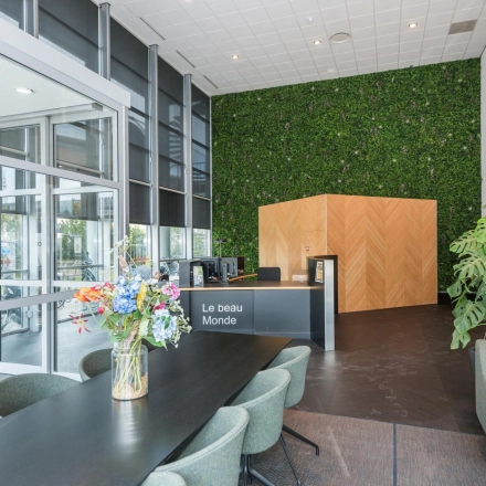 Modern reception area at Brandweerstraat 20-30 in Enschede featuring sleek furniture, greenery, and a welcoming desk. Ideal for office space rental seekers. The environment blends style with functionality seamlessly.