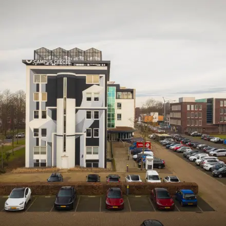 Exterior view of the office building at Brouwerijstraat 1 in Enschede with adjacent parking area, suitable for office space rental.