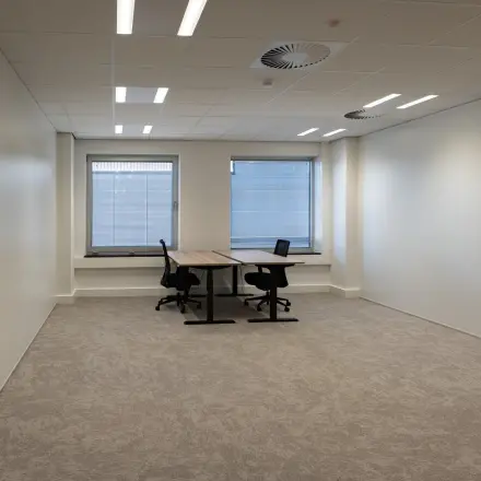 Bright office space for rent at Kuipersdijk 2-4, Enschede featuring two desks and chairs in a modern setting.