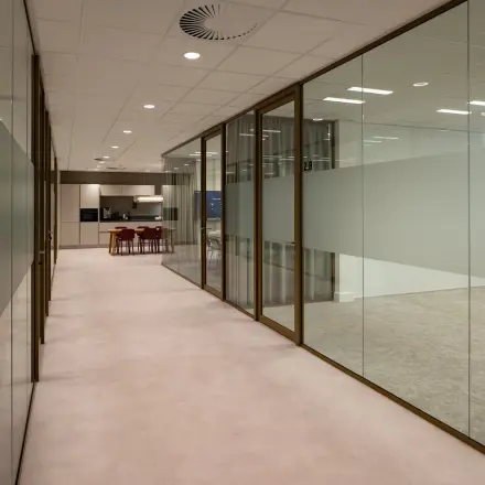 Modern office interior featuring glass walls, leading to a workspace area at Kuipersdijk 2-4, Enschede. Ideal for office space rental.