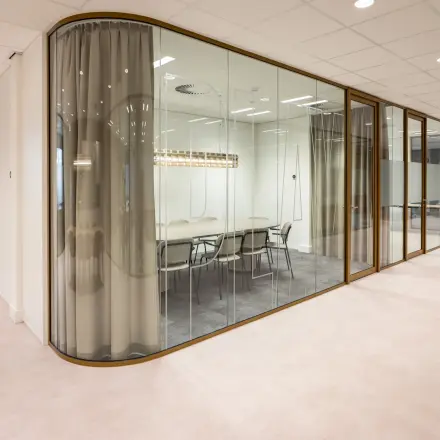 Modern office space rental at Kuipersdijk 2-4, Enschede, featuring a glass-walled conference room with a table and chairs.