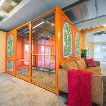 Bright office space with vibrant orange meeting pod and stylish seating, available for rent at Moutlaan 1-23, Enschede, ideal for office space rental.