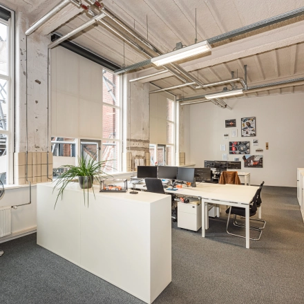 An office space with several workstations, potted plants, and large windows at Rigtersbleek-Zandvoort 10 in Enschede, available for rent.