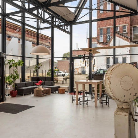 Spacious office space at Rigtersbleek-Zandvoort 10, Enschede, featuring large windows, a seating area, and high ceilings. Ideal for office space rental.