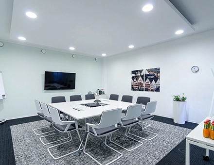 Modern office conference room at Mergenthaler Allee 15-21, Eschborn available for office space rental. Features a sleek table, comfortable chairs, and wall decor.