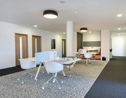 Modern furnished office space at Mergenthaler Allee 15-21 in Eschborn, featuring sleek desks with chairs and a comfortable seating area, ideal for office space rental.