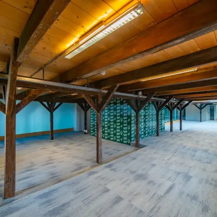 Spacious office to rent at Prins Hendrikkade 3, Franeker featuring an open floor plan with exposed beams and new carpeting, perfect for flexible office space rental opportunities.