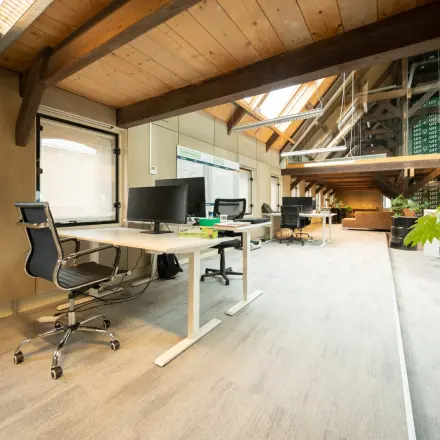 Office space at Prins Hendrikkade 3, Franeker, featuring a bright interior with modern workstations, natural wooden beams, and large windows. Ideal for office space rental.