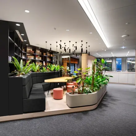 Modern office lounge at Junghofstraße 9, Frankfurt Center, featuring stylish seating and vibrant indoor plants, ideal for office space rental.