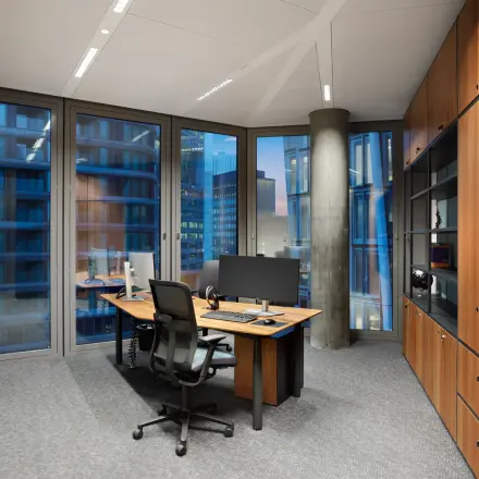 Modern office space with large windows, a wooden desk, ergonomic chair, and storage cabinets at Junghofstraße 9, Frankfurt Center; ideal for office space rental.