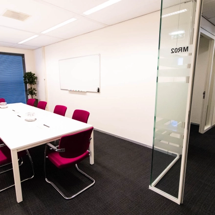 Bright office space at Kampenringweg 45, Gouda, featuring a conference table with red chairs, available for rent. Ideal for office space rental.