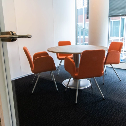 Furnished interior office space at Kampenringweg 45, Gouda, featuring a round table with four orange chairs, ideal for rent office space needs.