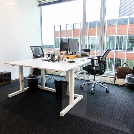 Modern furnished office space for rent at Kampenringweg 45, Gouda, featuring a desk with chairs, computers and office supplies near large windows.