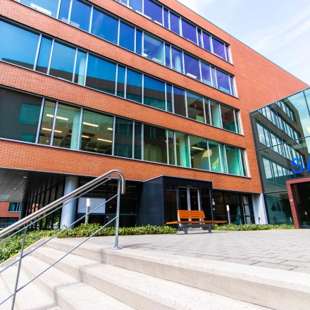 Exterior view of an office building at Kampenringweg 45, Gouda, showcasing large windows and entrance steps, ideal for those seeking office space rental.