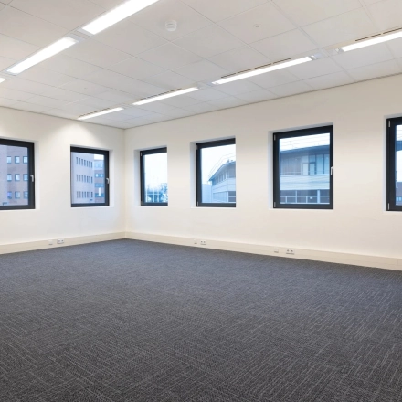 Bright office space at Zuidelijk Halfrond 1 in Gouda, available for rent with several large windows and modern carpeting.