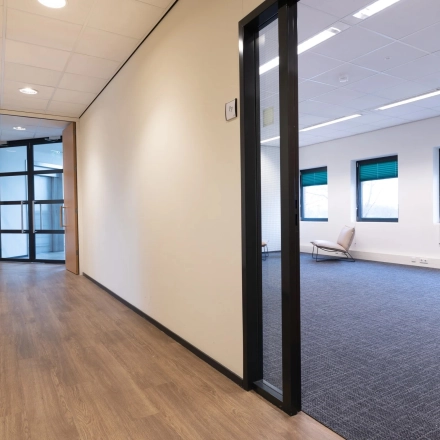 Interior view of an office space for rent at Zuidelijk Halfrond 1, Gouda. The room features large windows and minimal furnishings, suitable for office space rental.