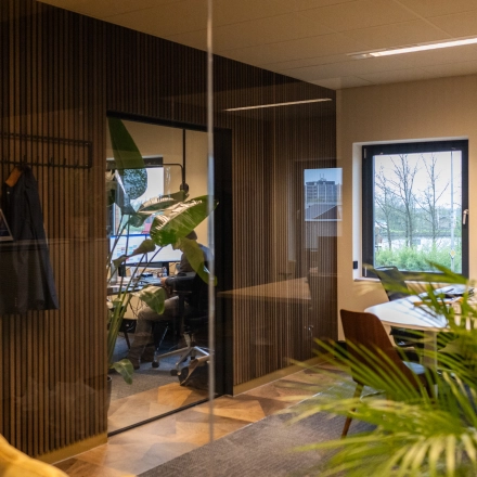 Modern office space available for rent at Zuidelijk Halfrond 1, Gouda, featuring natural light, plants, and sleek furnishings.