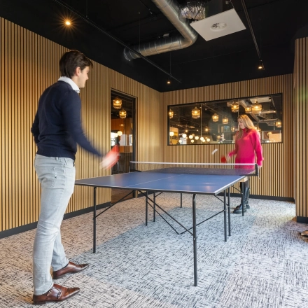 Two people enjoy a game of table tennis in a bright office space at Zuidelijk Halfrond 1, perfect for rent office space with engaging amenities.