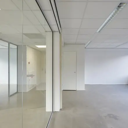 Bright, unfurnished office space available for rent at Schweitzerlaan 12, Groningen with large windows and glass partitions.