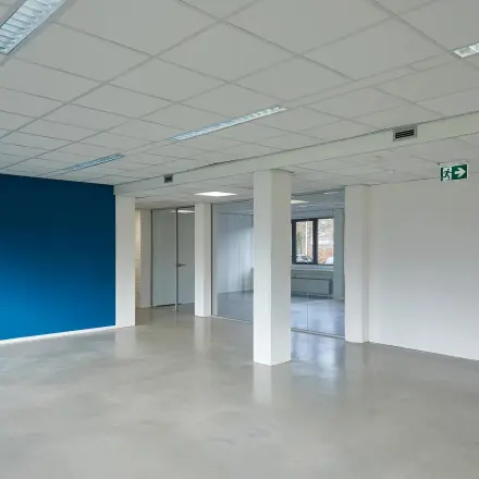 Unfurnished interior office space with a blue accent wall and large windows at Schweitzerlaan 12, Groningen, available for rent office space.