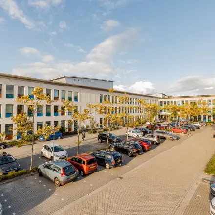 Exterior view of the office at Zernikepark 12, Groningen, featuring a parking area with multiple cars.