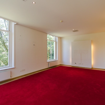 Spacious office with large windows and a red carpet at Prinsen Bolwerk 1, suitable for office space rental near Haarlem Centraal Station.