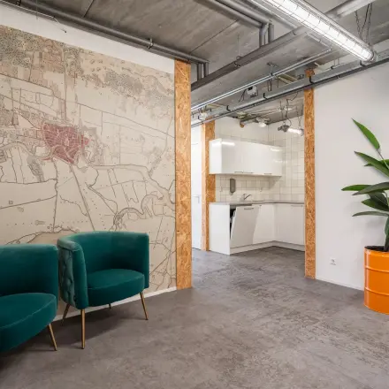 Office interior at Waarderweg 52 in Haarlem Waarderpolder, featuring a map mural, green chairs, and a kitchenette. Ideal for office space rental.