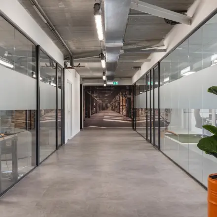 Bright office space for rent at Waarderweg 52, Haarlem Waarderpolder, with glass-walled workspaces and a potted plant adding a touch of greenery.