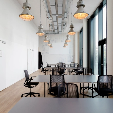 Spacious office space rental at Versmannstraße 4 in Hamburg Hafencity with modern lighting and desks, ideal for collaborative work. Ideal office to rent for dynamic teams.