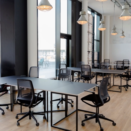 Spacious office to rent at Versmannstraße 4 in Hamburg Hafencity, featuring large windows and modern furniture suitable for collaborative work sessions. Ideal for office space rental.