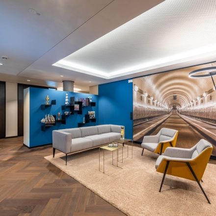Stylish office lounge with modern furnishings, vibrant decor, and a tunnel mural, ideal for office space rental in Hamburg Old Town.
