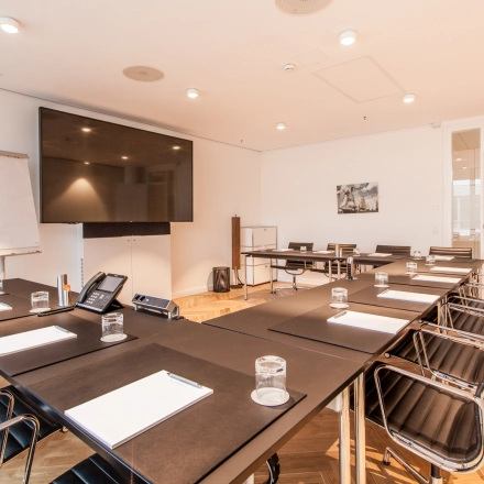 Spacious conference room at Ballindamm 39, Hamburg Old Town, ideal for office space rental. Features sleek tables, chairs, and a large screen for presentations.