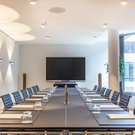 Spacious conference room at Ballindamm 39, Hamburg Old Town, featuring a long table, chairs, and presentation screen, ideal for office space rental.