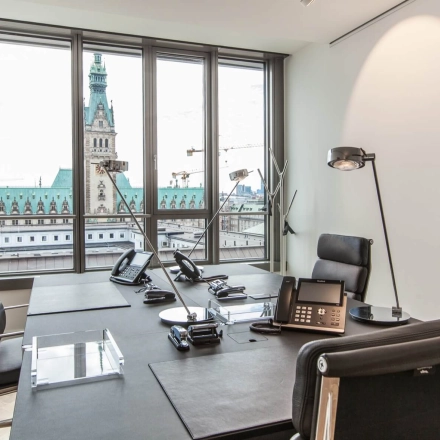 Modern furnished office space rental at Ballindamm 39 in Hamburg Old Town, featuring large windows with a city view and professional desks.