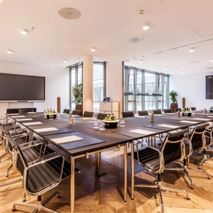 Modern conference room available for office space rental at Ballindamm 39, Hamburg Old Town, featuring sleek furnishings and airy windows.