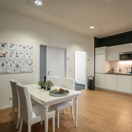 Interior view of a furnished office space at Raboisen 38, Hamburg Old Town, featuring a dining area and kitchenette, available for office space rental.