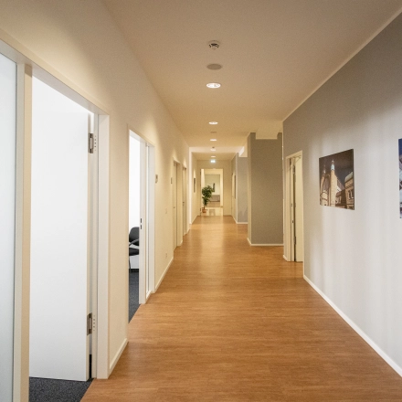 Bright hallway at Raboisen 38, Hamburg Old Town, ideal for office space rental. The corridor leads to various rooms, featuring artwork on the walls.