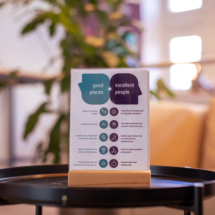 Bright office interior at Ceintuurbaan 2, Harderwijk, showcasing cozy lounge area, ideal for rent office space. Features a stylish table with informational brochure, set against a backdrop of soft lighting and greenery.