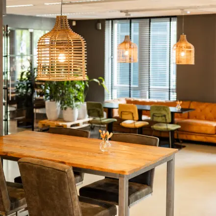 Stylish and furnished office space for rent at Demmersweg 3, Hengelo, featuring modern seating, ambient lighting, and wooden tables in a welcoming lounge area.