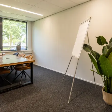 Furnished office space for rent at Jan Tinbergenstraat 202, Hengelo, featuring a wooden table, chairs, and a large window with natural light.