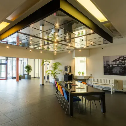 Modern office interior at Lansinkesweg 4, Hengelo, featuring a stylish table with colorful chairs available for office space rental.