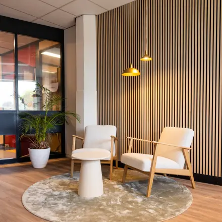 Modern office lounge area at Lansinkesweg 4, Hengelo, featuring stylish seating and warm lighting, perfect for office space rental.