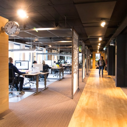 A modern office space with people working at desks, located at Franciscusweg 219, Hilversum. Ideal for office space rental, it offers a productive work environment.