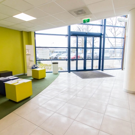 Bright entrance area at Franciscusweg 219 in Hilversum, ideal for office space rental, featuring colorful seating and large windows for natural light.