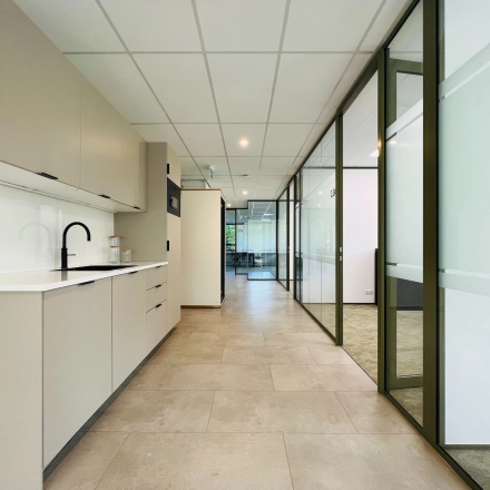 Modern office space rental at Marathon 2, Hilversum, featuring a sleek interior with glass partitions and cabinetry.