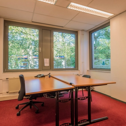 An office to rent in Hilversum featuring two desks and chairs, with large windows offering natural light. Ideal for office space rental at Mozartlaan 27.