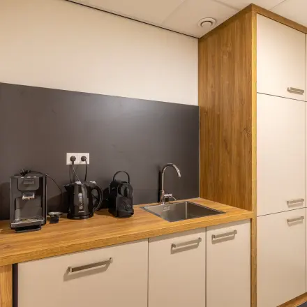 Compact office pantry featuring a sink and coffee machines, available for office space rental at Mozartlaan 27, Hilversum.
