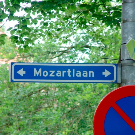 Street sign pointing to Mozartlaan in a leafy area of Hilversum.